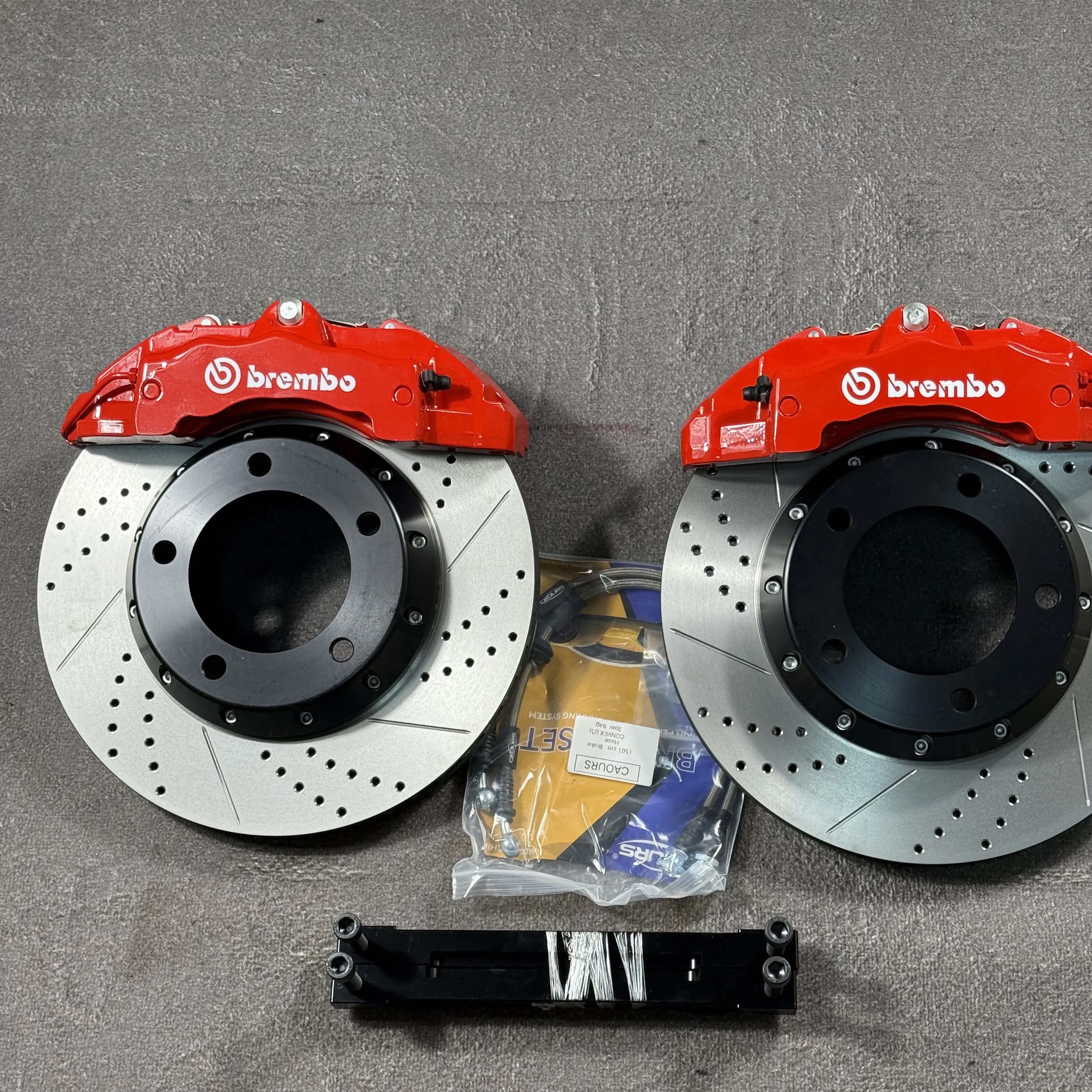 Два красных шестипоршневых суппорта Brembo с перфорированными дисками с насечками, армированными шлангами и кронштейном