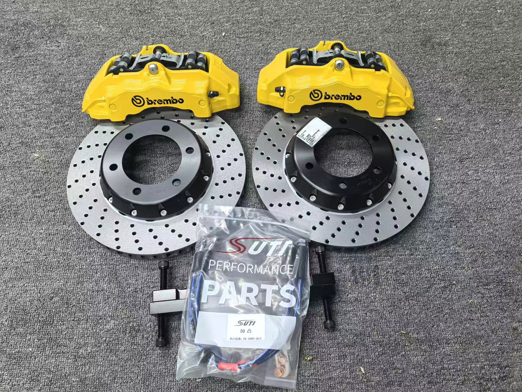Шестипоршневые суппорта Brembo жёлтого цвета с перфорированными двухсоставными дисками, кронштейнами и тормозными шлангами