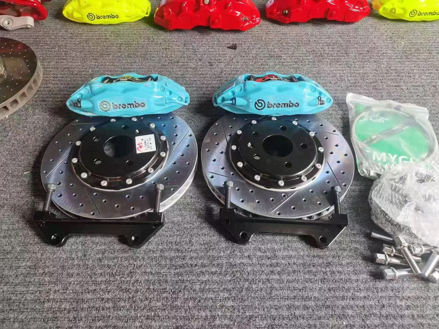 Комплект Brembo F40: два четырёхпоршневых суппорта бирюзового цвета, составные перфорированные диски с насечками, кронштейны, крепёж и шланги
